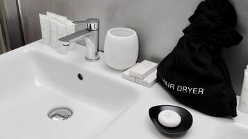 Un lavandino in bagno con articoli da toilette, un sacchetto per asciugacapelli e una tazza.