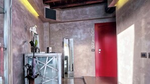 Un vestíbulo moderno con una puerta roja, un jarrón grande con flores y una escultura de vidrio.