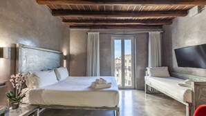 Una habitación de hotel con cama, escritorio, televisor y balcón con vistas.