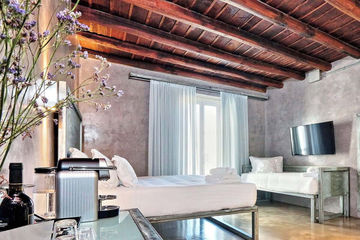 Una habitación de hotel moderna con una cama grande, una zona de estar, un televisor y un baño.