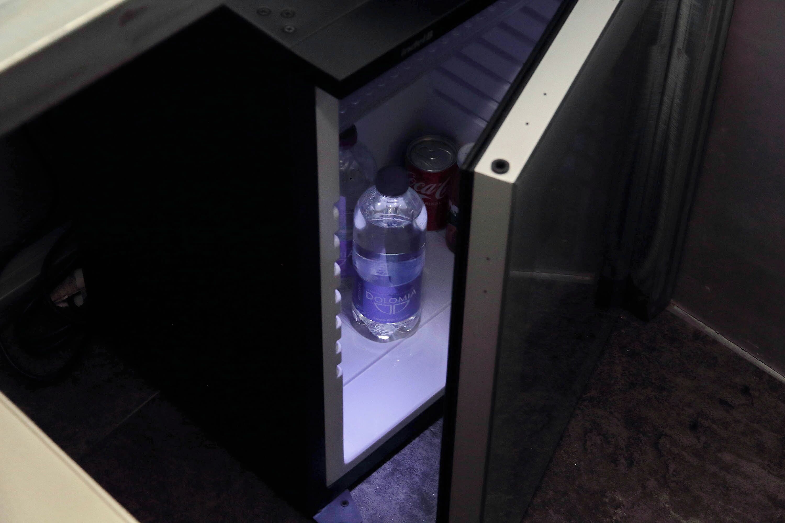 A refrigerator with a bottle of water and a can of Coca-Cola inside.
