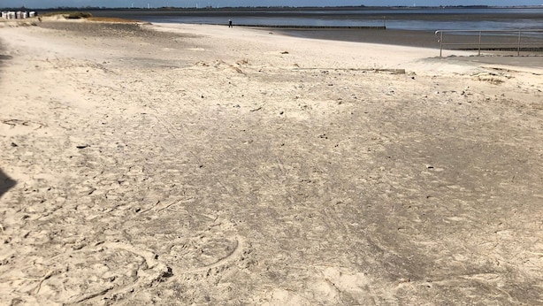 A sandy beach with footprints and a metal railing. - Apartment 'Wilde' with Wi-Fi (Hooksiel)