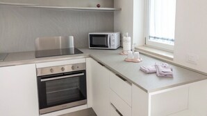 A compact kitchen with a built-in oven, microwave, and a small countertop. - Color Dream Residence- Intimate Suite Pink (Capitolo)