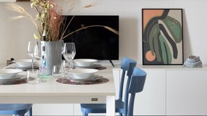 A modern dining area with a white table set for four, blue chairs, and a vase of dried flowers. - Color Dream Residence- Intimate Suite Pink (Capitolo)