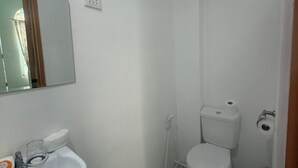 Une petite salle de bain blanche, avec un lavabo, un miroir et des toilettes.