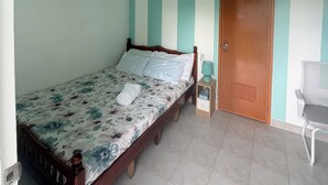 Une chambre à coucher avec un lit, un ventilateur de plafond, une porte en bois et une chaise.
