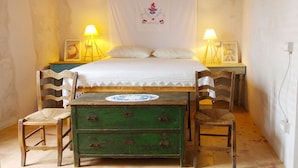 Une chambre à coucher avec un lit, deux chaises, une commode verte et deux lampes de chevet.
