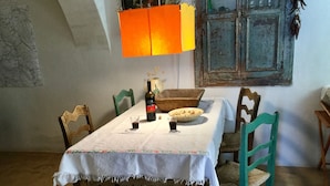 Une table à manger recouverte d’une nappe blanche, une bouteille de vin, des verres et un plat de nourriture.