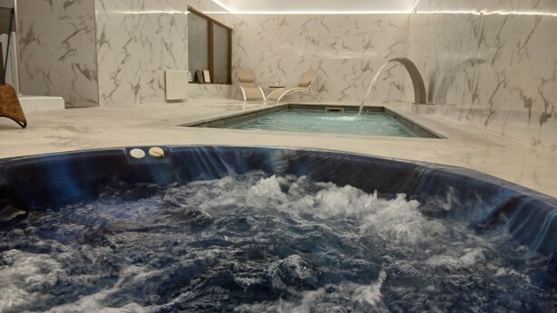 A spa area with a hot tub, marble walls, and a small seating area. - la casona encanto rural (Llanes)