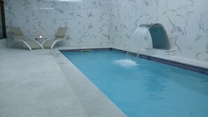 An indoor swimming pool with a marble wall and a small waterfall feature. - la casona encanto rural (Llanes)