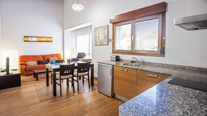 A modern kitchen with granite countertops, a built-in oven, and a window with blinds. - la casona encanto rural (Llanes)