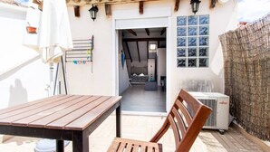 A patio with a wooden table and chairs, a white umbrella, and a wall-mounted drying rack. - Studio for couples with terrace on the beach (València)