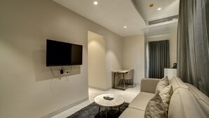 Ein modernes Wohnzimmer mit Flachbildfernseher, einer Couch, einem Couchtisch und einem Essbereich.