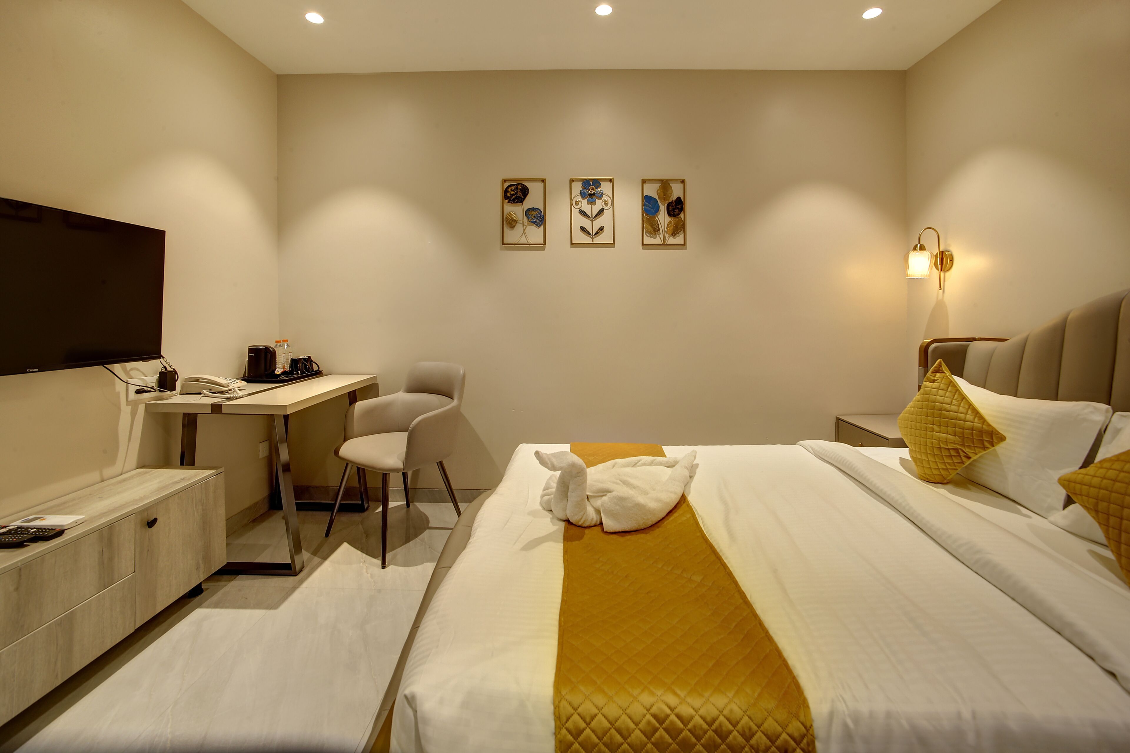 A hotel room with a bed, desk, chair, and artwork on the wall.