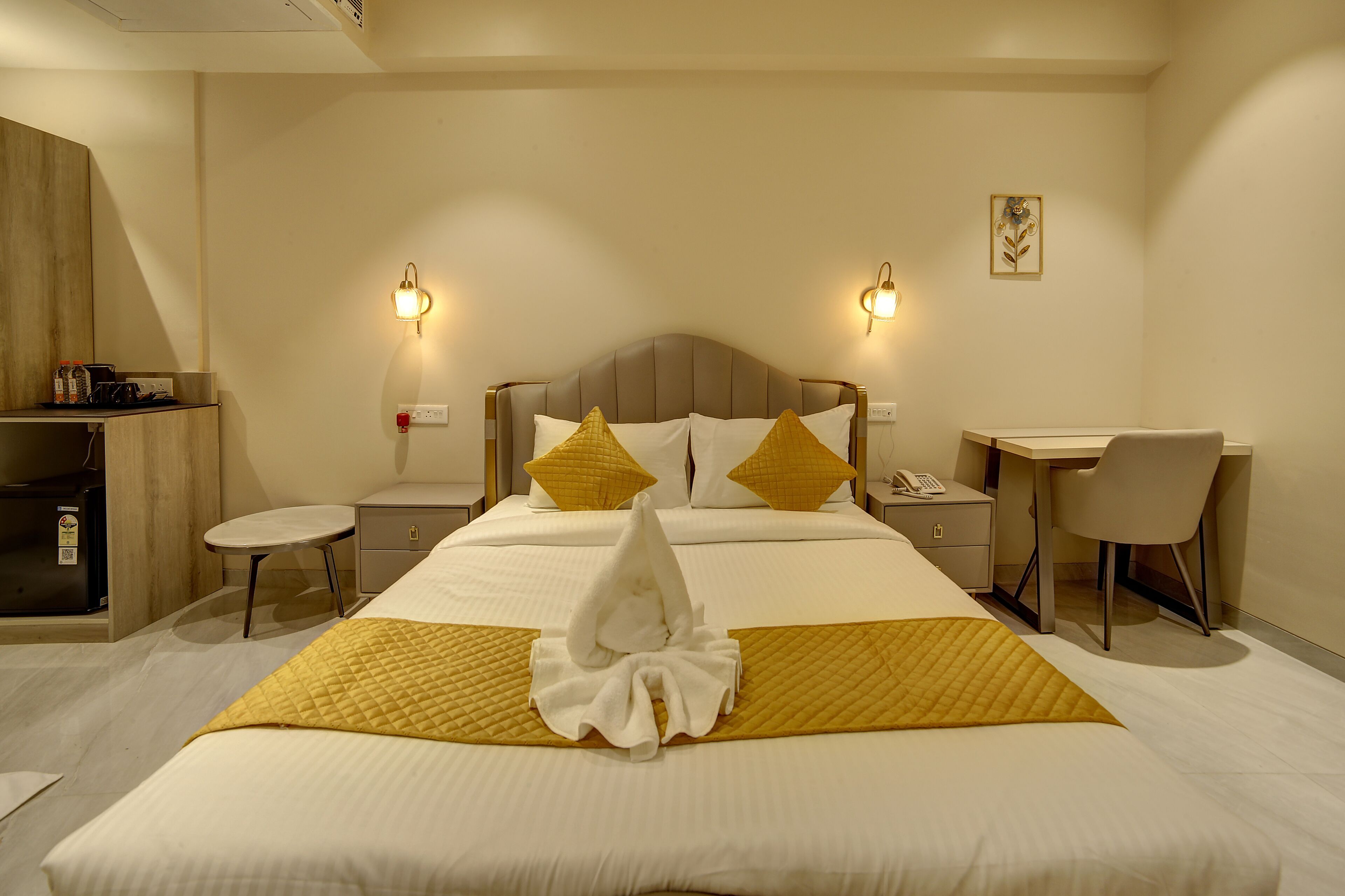 Quarto de hotel com cama, mesas de cabeceira, escrivaninha e uma cadeira.