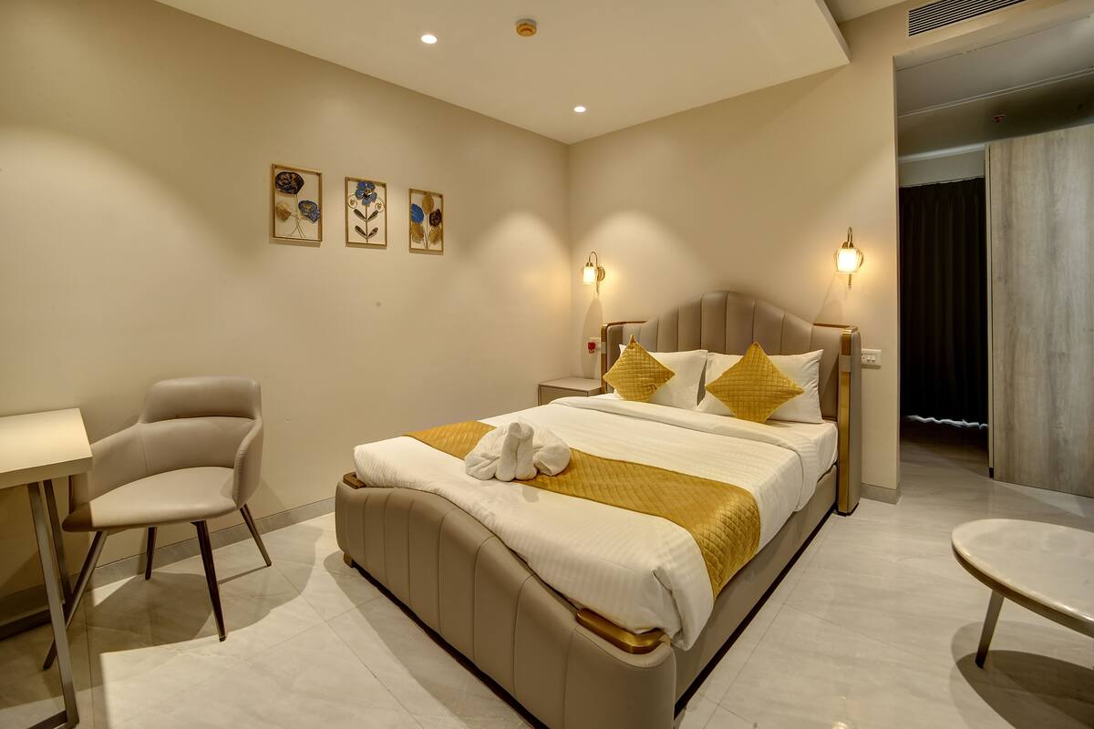 A hotel room with a bed, bedside table, chair, and artwork on the wall.