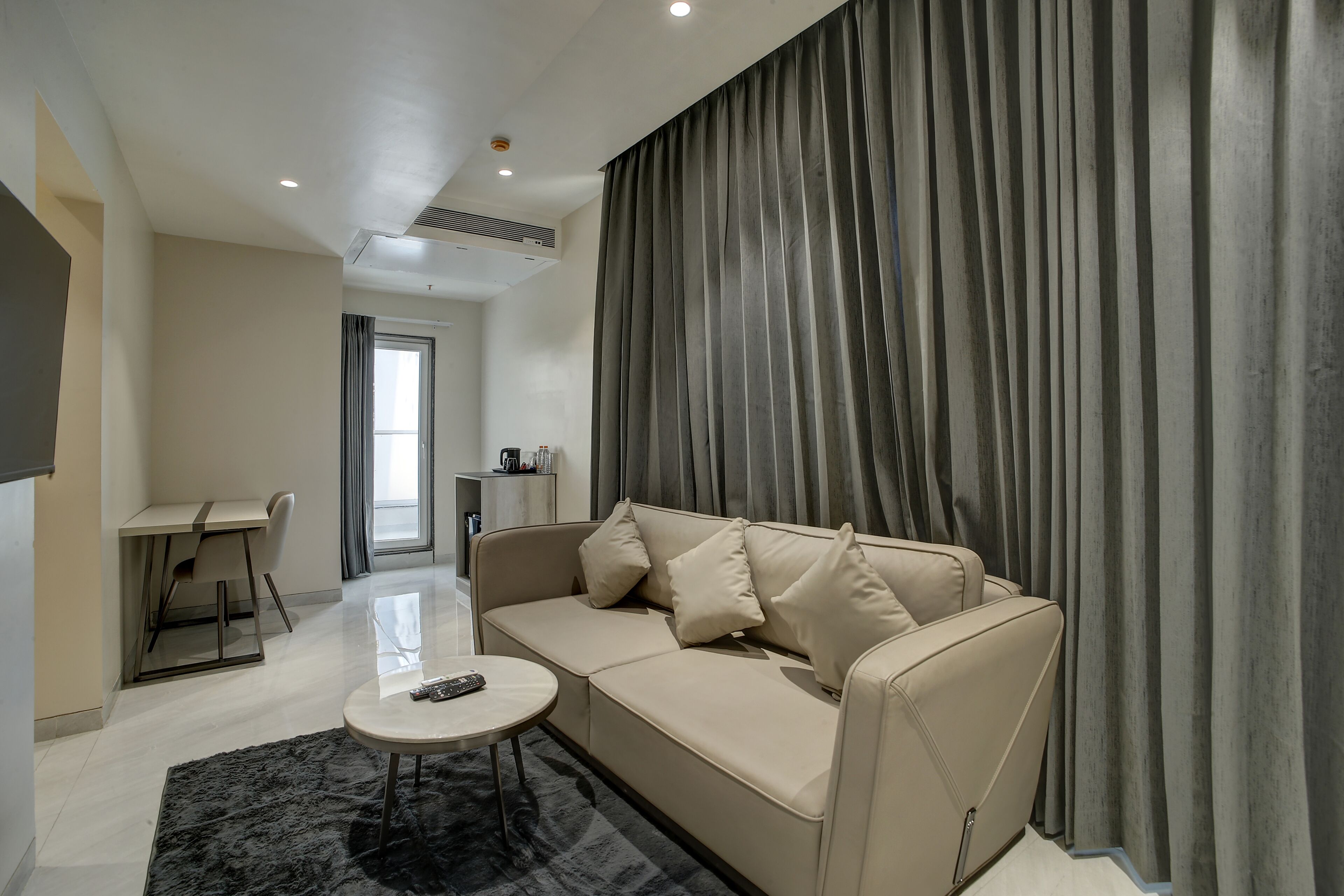 A modern living room with a sofa, a coffee table, and a dining area.