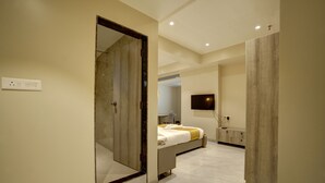 Ein modernes Hotelzimmer mit großem Spiegel, einem Bett, einem Fernseher und einem Badezimmer mit Toilette und Waschbecken.