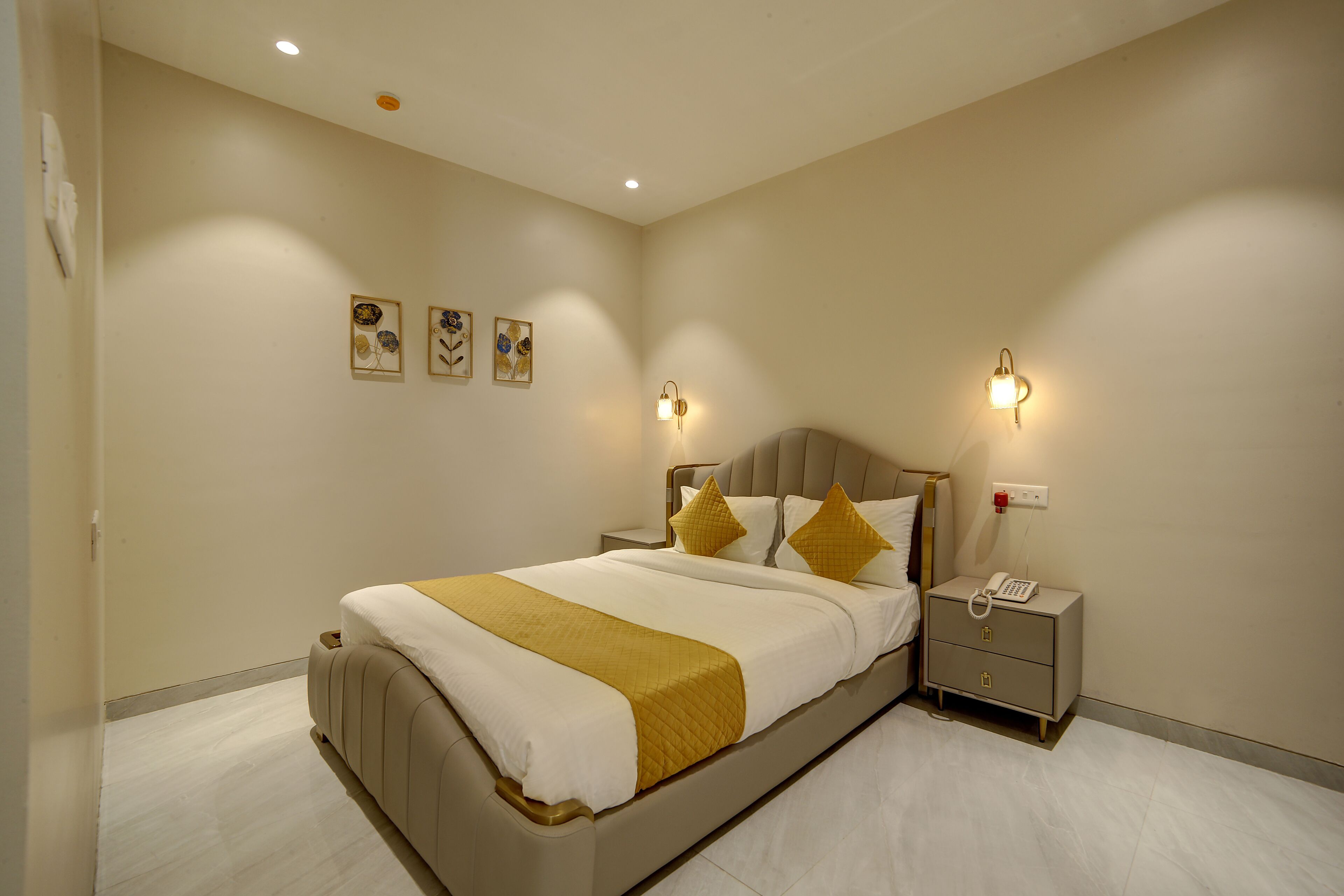 Un dormitorio con cama, mesitas de noche, lámparas de pared y obras de arte en la pared.