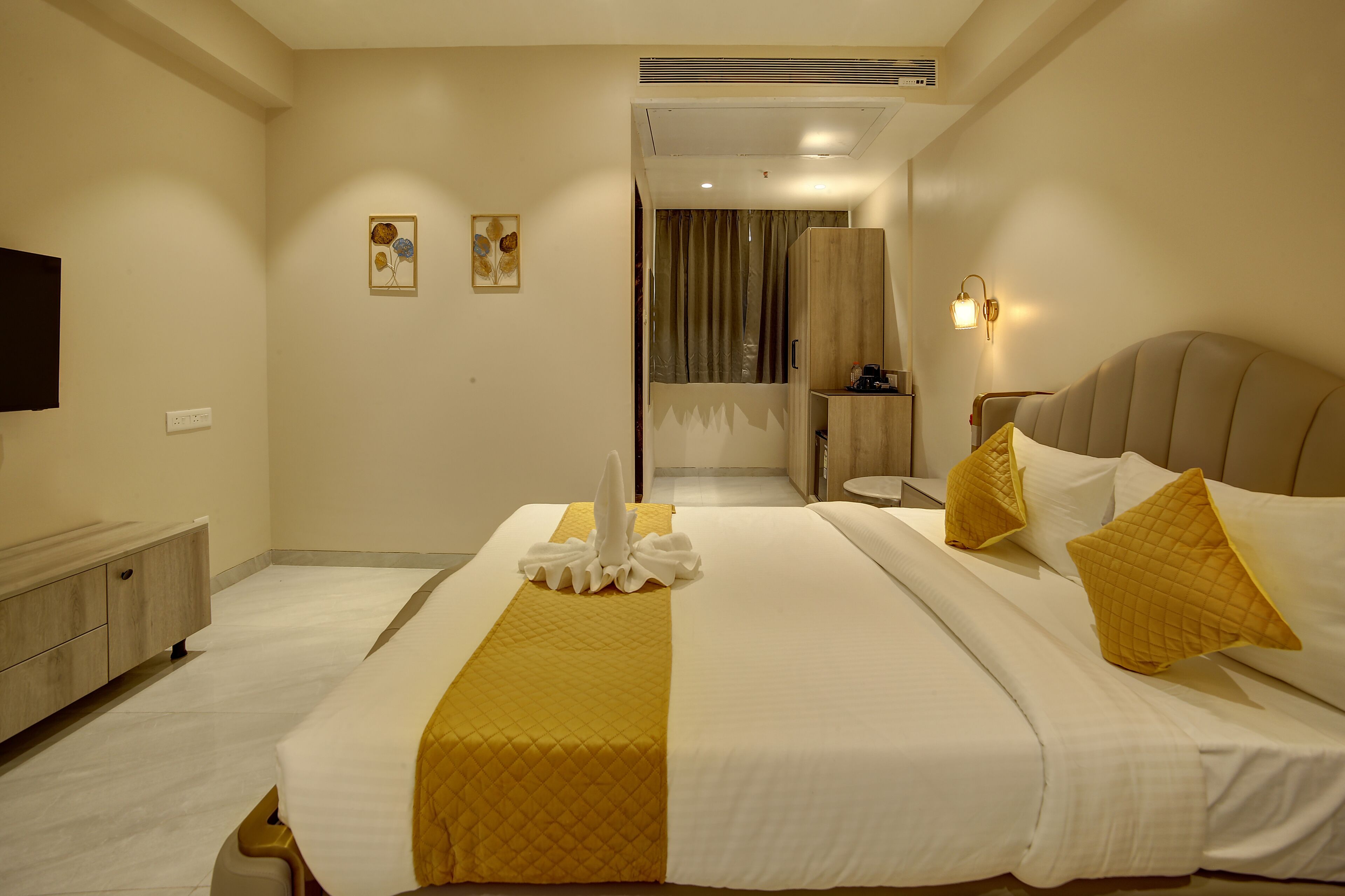 A hotel room with a bed, bedside table, and a television on the wall.