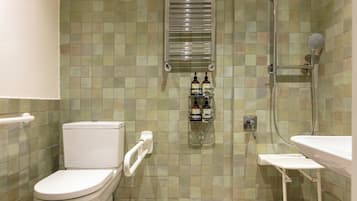 Un baño con inodoro, ducha y lavabo. Hay botellas en la pared.