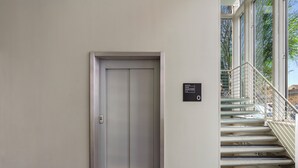 A modern elevator with a closed door, a staircase with metal railings, and a sign indicating the floor number. - Bob W Rome Testaccio (Rome)