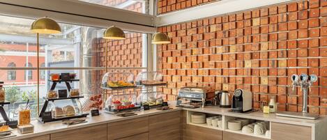 A breakfast bar with a brick wall, wooden cabinets, and a coffee machine.