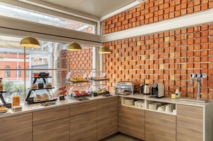Eine Frühstückstheke mit Backsteinwand, Holzschränken und einer Kaffeemaschine.