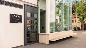 A modern hotel entrance with a glass facade, a black door, and a sign indicating the name 'BOB W. Rome Testaccio Hotel'. - Bob W Rome Testaccio (Rome)