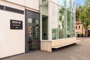 Ein moderner Hotel Eingang mit Glasfassade, einer schwarzen Tür und einem Schild mit dem Namen 'BOB W. Rome Testaccio Hotel'.