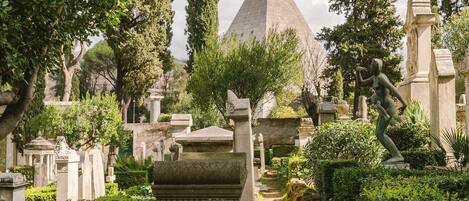 Un cimetière abritant un monument imposant en forme de pyramide, entouré de diverses statues et pierres tombales.