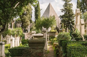 Un cimitero con un imponente monumento a forma di piramide, circondato da diverse statue e lapidi.
