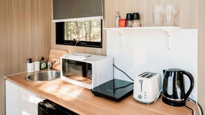 Une petite cuisine équipée d’un four à micro-ondes, d’un grille-pain, d’une bouilloire et d’un petit évier.