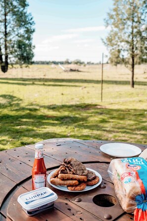 Ein Picknick mit Speisen, einer Ketchupflasche, einem Joghurtbecher und einer Brottüte auf einem Holztisch.