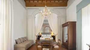 A room with a bed, a sofa, a dining table with chairs, a chandelier, and a large mirror. - Villa Bartolini Baldelli - Authentic XV century villa with garden and pool (Toscana)