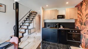 A modern kitchen with black appliances, wooden cabinets, and a marble floor. - Lyon Est Élégance - Parking & Comfort (Meyzieu)