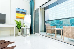 A modern hotel room with a balcony, a desk, a chair, a potted plant, and a large window with a city view. - Executive stay with hotel facilities (Dubai)
