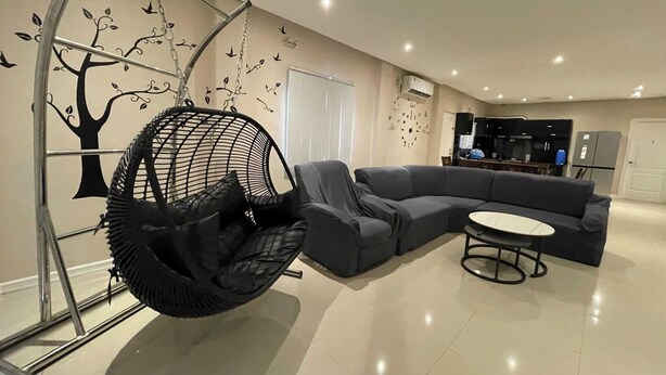 Een moderne woonkamer met een grijze modulaire bank, een hangstoel en een kleine ronde tafel.
