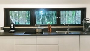 Eine Küche mit Fenster, Spüle, Herd und Kaffeemaschine.