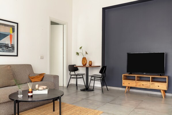 Un salon comprenant un canapé, une table basse, un meuble pour la télévision, ainsi qu’un coin repas avec des chaises et une table.
