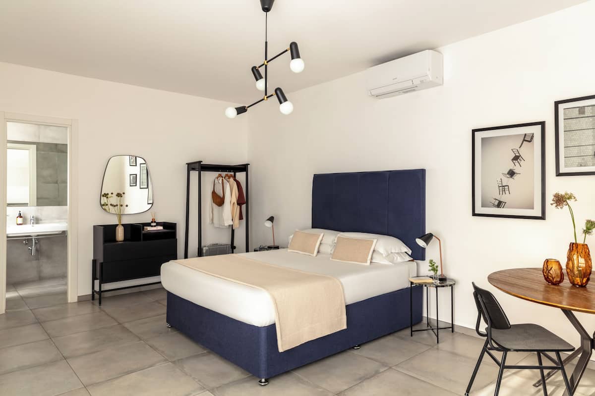 A modern bedroom with a bed, bedside table, and a small round table with chairs.