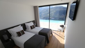 Une chambre d’hôtel avec deux lits, une télévision et une vue sur un paysage montagneux.