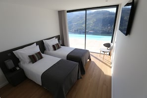 Habitación de hotel con dos camas, televisor y vista a un paisaje montañoso.