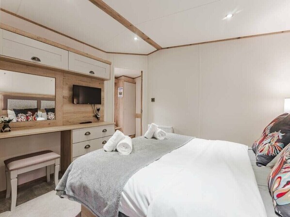 Une chambre d’hôtel avec un lit, un bureau avec une télévision et un banc.