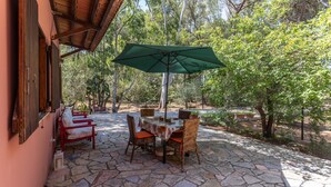 Un patio al aire libre con suelo de piedra, una mesa con sillas y un paraguas verde.