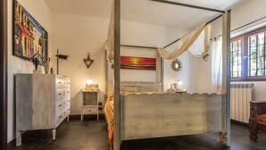 Una cama con dosel, un aparador, una mesita de noche y un cuadro en la pared.
