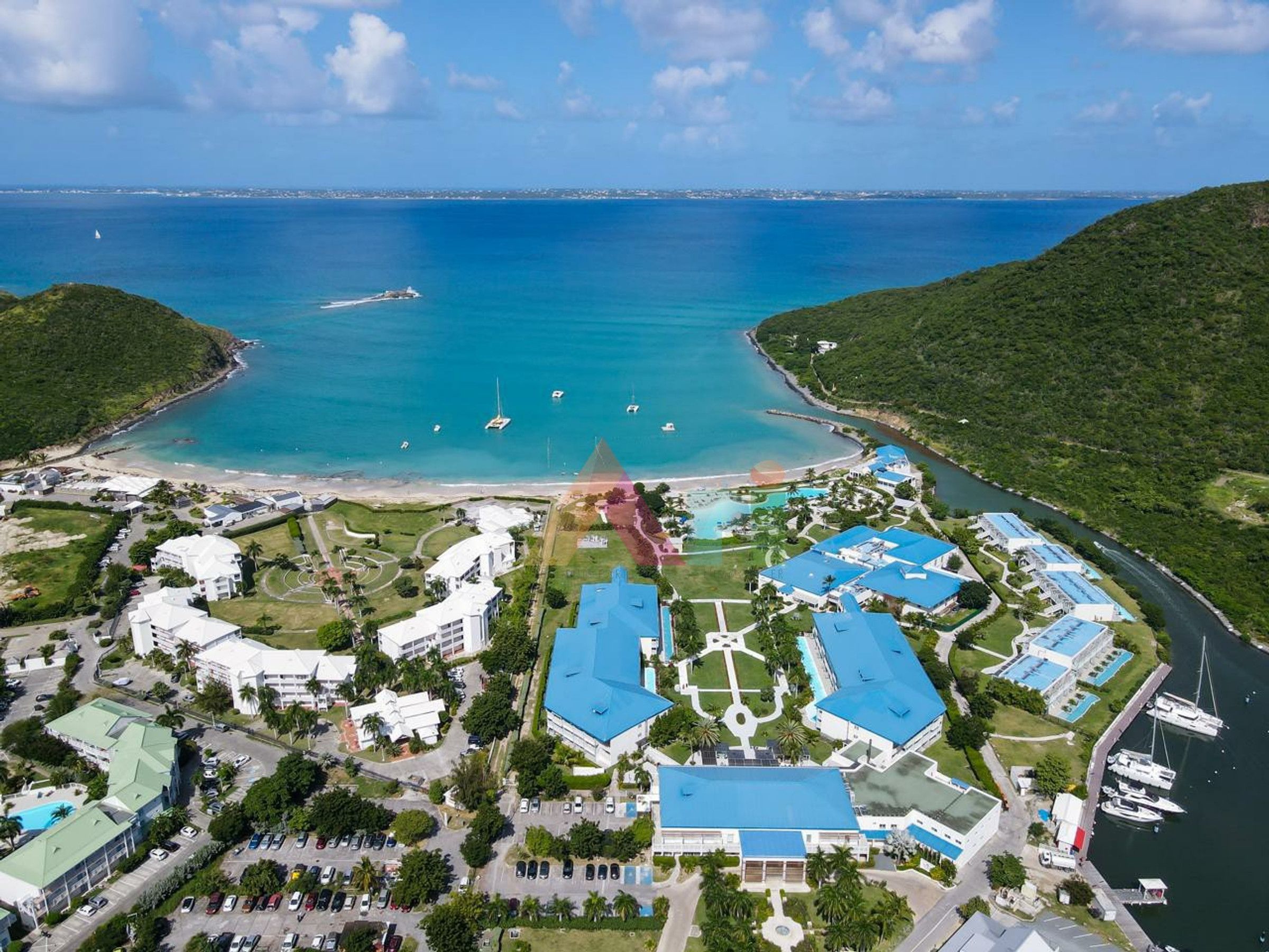 An aerial view of a coastal resort with multiple buildings, a marina, and a beach.