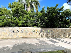 A stone wall with the inscription "ANSE MARCEL" and a parking area with directional arrows. - Elegant Suite in Anse Marcel - Comfort and Escape (Saint-Martin)