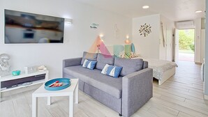 A modern living room with a grey sofa, a small white table, and a ceiling fan. - Studio in Anse Marcel (Saint-Martin)