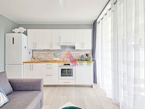 A modern kitchen with white cabinets, a wooden countertop, and a built-in oven. - Studio in Anse Marcel (Saint-Martin)